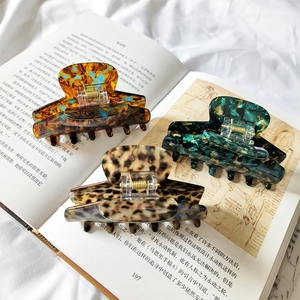 Three-piece acetate hair claw clips with leopard and marble patterns on open book