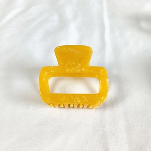Detail view of yellow marble textured square acetate hair claw clip on white fabric