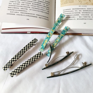 Set di fermagli francesi in acetato con motivi a scacchi e geometrici su un libro aperto