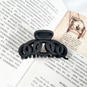 Close-up of a matte black chain hair claw clip placed on vintage book pages