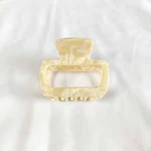Detail view of a cream marble acetate hair claw clip with a hollow rectangular design