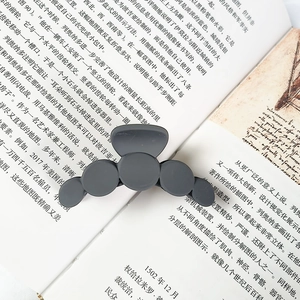 Matte dark grey claw clip featuring five circular geometric patterns on an open book