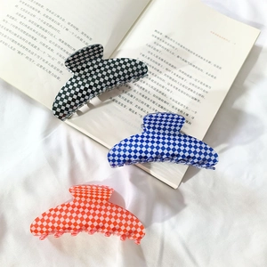 Macro detail of large checkerboard hair claws in black, blue, and orange patterns