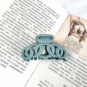 Close-up of matte Morandi blue chain-link hair claw clip on an open book background
