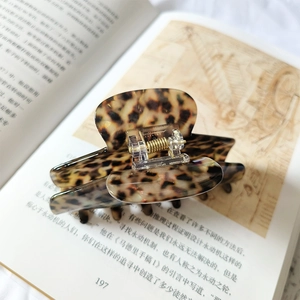 Detailed view of leopard print acetate hair claw with durable metal spring on vintage book