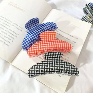 French checkerboard hair claws in blue, orange, and black on a book for hair styling