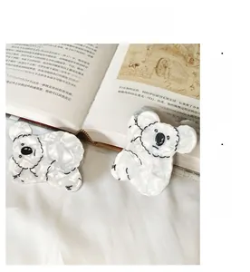 Gros plan de pinces à cheveux koala en acétate blanc sur un fond de livre ouvert