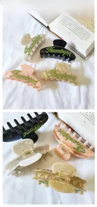 Gros plan d'une grande pince à cheveux en acétate avec lettres en cristal et ressort métal