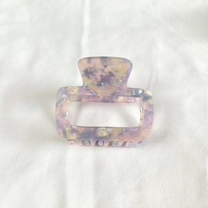 Close-up of square acetate hair claw clip with purple and pink marble texture
