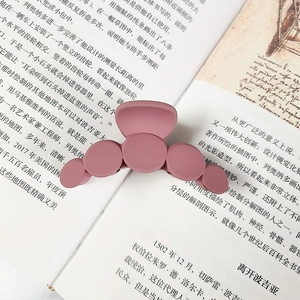 Detail of a matte mauve purple claw clip with round design on an open book