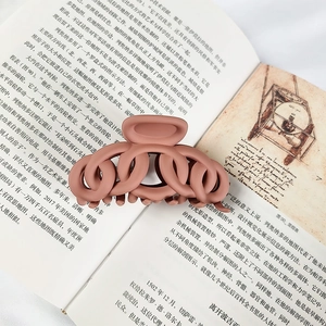 Close-up of matte Morandi pink hair claw clip with twisted chain design on open book