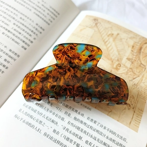 Detail view of large amber and translucent blue resin hair claw clip on a book