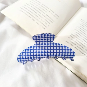 Detail of blue and white checkered hair claw clip on soft white fabric background