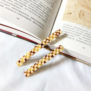 Dettaglio di due fermagli per capelli in acetato a scacchi gialli su un libro con clip in metallo