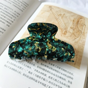 Detail of 9cm large marble pattern hair claw clip on vintage book background