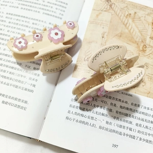 Pince à cheveux fleur crème élégante avec pétales roses et strass sur fond de livre