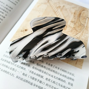 Close-up of a 9cm black and white marble acetate hair claw clip on a book page