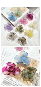 Detail showing various iridescent flower hair claws in multiple colors on white fabric