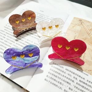 Elegant heart hair claws in amber, white, blue and rose red on an open book