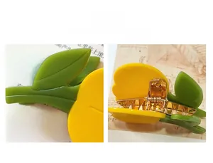 Détail du ressort métallique doré et de la texture en acétate de la pince à cheveux tulipe