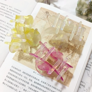 Three pearlescent acetate flower hair claws in pastel yellow, cream, and lavender pink