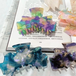 French style acetate claw clips with marble pattern in multiple colors on an open book