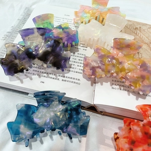 Elegant marble-patterned acetate hair claw clips displayed on an open book