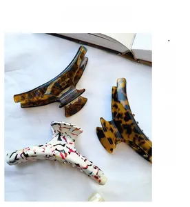 Three assorted acetate claw clips in tortoise shell and ink patterns on white silk