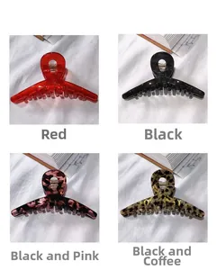 Macro detail of large acetate hair claws in red, black, and leopard patterns on white fabric