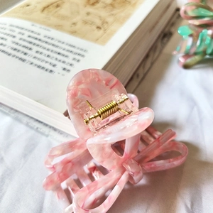Eleganter Haarklammer mit rosa Marmorschleife auf Buchhintergrund für französisches Styling