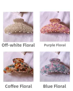 Détail de grandes pinces à cheveux en acétate avec motifs floraux crème, violet, brun et bleu