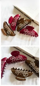 Detailed close-up of pearl Bride lettering on elegant burgundy hair claw clips