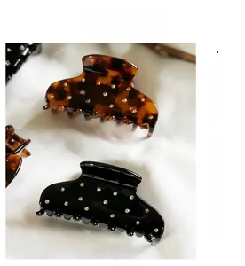 Détail des pinces à cheveux en acétate noir et écaille avec des strass brillants