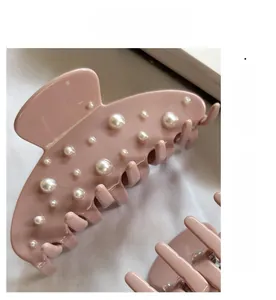 Détail de la pince à cheveux rose poudré avec perles sur fond en tissu blanc doux