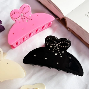 Elegant rhinestone bow claw clips in pink, black, and beige for stylish women's hair styling