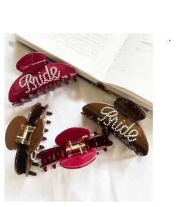 Close-up of pearl Bride lettering on dark red and brown French style hair claw clips