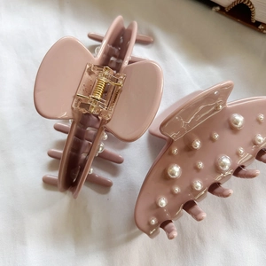 Grandes pinces à cheveux rose poudré avec perles élégantes sur tissu blanc texturé