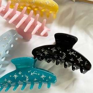 Elegant starry rhinestone acetate shark hair claws in multiple colors on white fabric