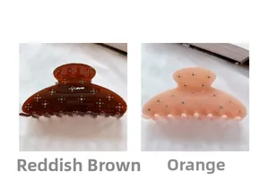 Detail of red-brown and orange acetate hair claws featuring sparkling star-pattern rhinestones