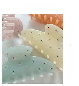 Macro detail of large acetate hair claws with floral rhinestone patterns in pastel colors