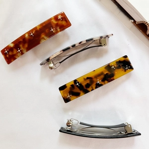 Set of four tortoise shell hair barrettes with floral rhinestones on a white fabric backdrop