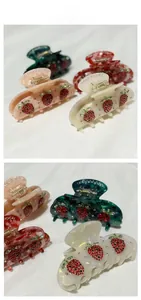 Detail of strawberry acetate hair claw clip with red and green rhinestones
