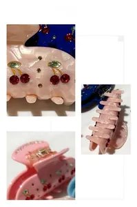 Detail view of elegant cherry hair claw clips with rhinestones on marble texture finish
