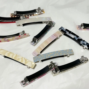 Assorted acetate french hair clips in marble and tortoise patterns on white fabric