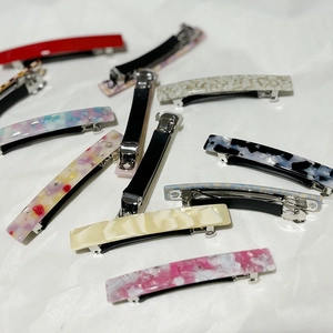 Various acetate spring hair clips with colorful patterns on a white fabric background