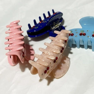 Elegant cherry rhinestone hair claws in multiple marble colors on a white fabric background