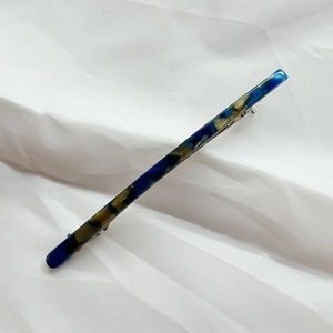 Detail view of large marble texture blue and amber acetate spring hair clip on white cloth