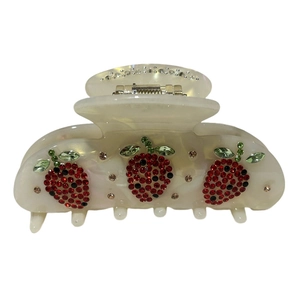 Creamy acetate hair claw with sparkling rhinestone strawberry patterns on white background