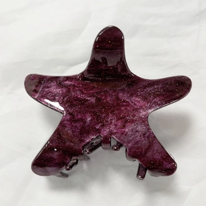 Detailed view of starfish hair claw with purple marble texture and gold glitter accents