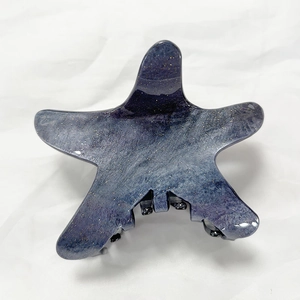 Macro detail of star-shaped hair claw with blue-purple starry sky marble texture and glitter